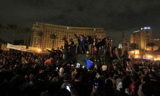 Anti-Mursi protesters stand on a riot police vehicle after they seized it on the Kasr Elnile bridge to Tahrir square in Cairo