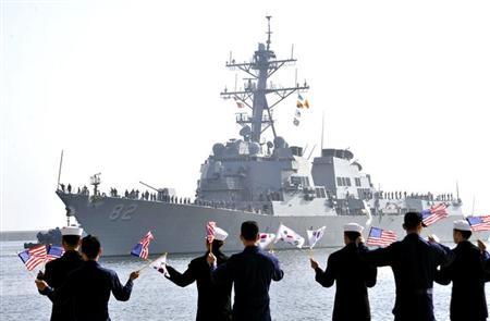 The guided missile destroyer USS Lassen arrives as South Korean navy sailors wave flags at a naval port in Donghae