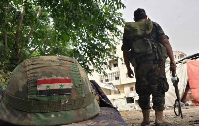 A Syrian soldier stands near an army helmet decorated with the Syrian flag in the Jab al-Jandali district of the central city of Homs on May 7, 2014 after Syrian government forces regained control of the city. The evacuation of rebel-held ts of Syria's Homs began today under an unprecedented deal which hands back control to the government weeks before the controversial June 3 election expected to return President Bashar al-Assad to office. AFP PHOTO/STR