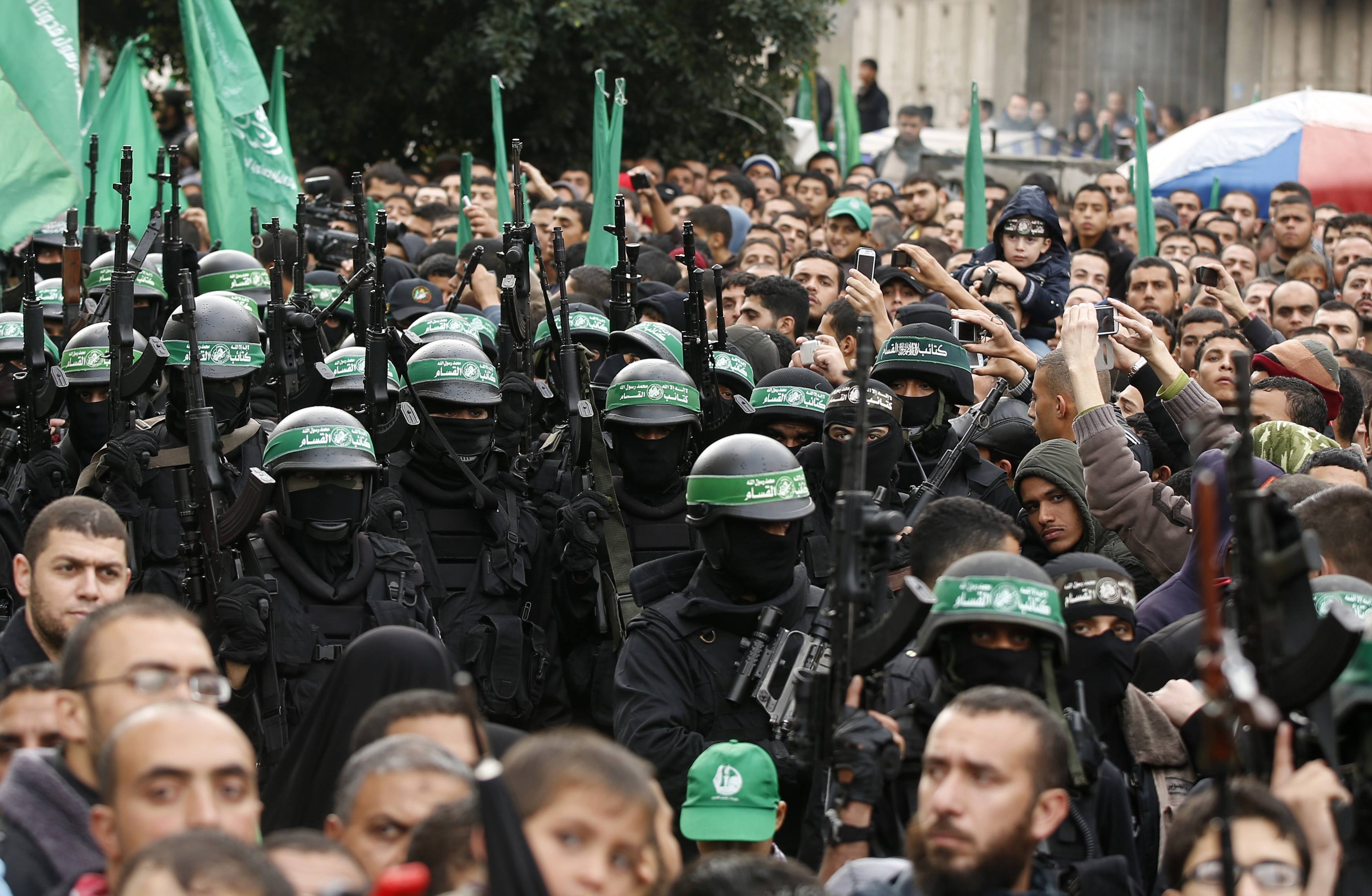 People watch as Palestinian members of al-Qassam Brigades, the armed wing of the Hamas movement, take part in a military parade marking the 27th anniversary of Hamas' founding, in Gaza City December 14, 2014.  REUTERS/Mohammed Salem